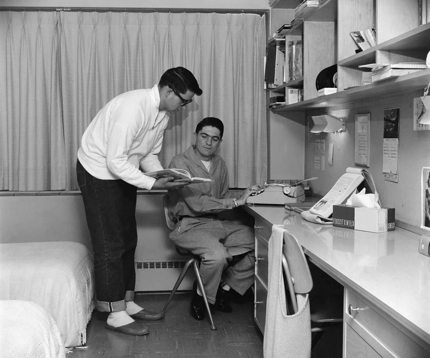 Two students working on a writing project in a dorm room